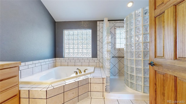 bathroom with a textured wall, walk in shower, a bath, and tile patterned floors