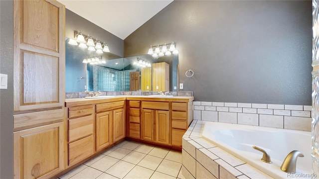 full bath featuring a garden tub, a sink, vaulted ceiling, tile patterned floors, and double vanity