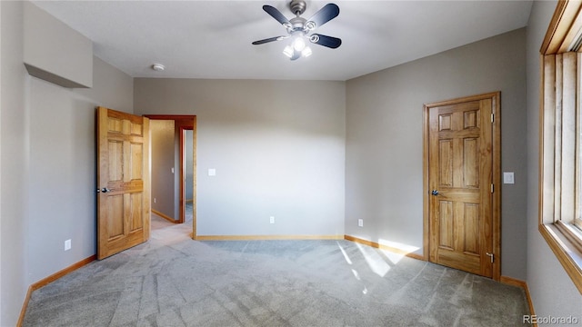 carpeted spare room with a ceiling fan and baseboards