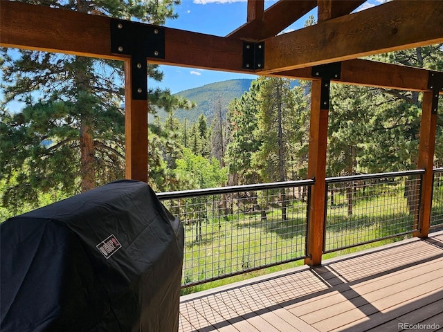 deck with a grill and a wooded view