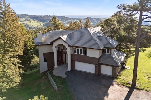 23655 Currant Dr, Golden, CO 80401 - view of front of property featuring stucco siding, asphalt driveway, a front yard, a chimney, and an attached garage