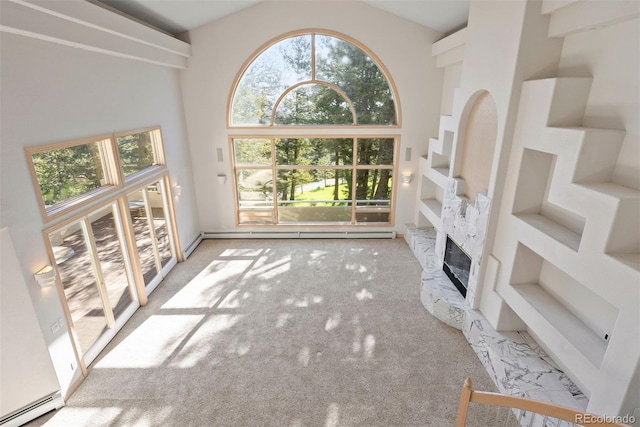 23655 Currant Dr, Golden, CO 80401 - unfurnished living room featuring a towering ceiling, carpet floors, a baseboard heating unit, a stone fireplace, and a baseboard radiator