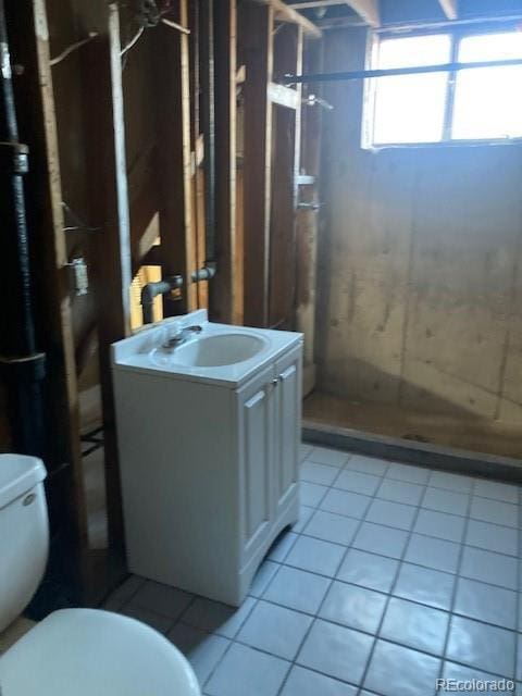 bathroom featuring tile patterned floors, vanity, toilet, and walk in shower