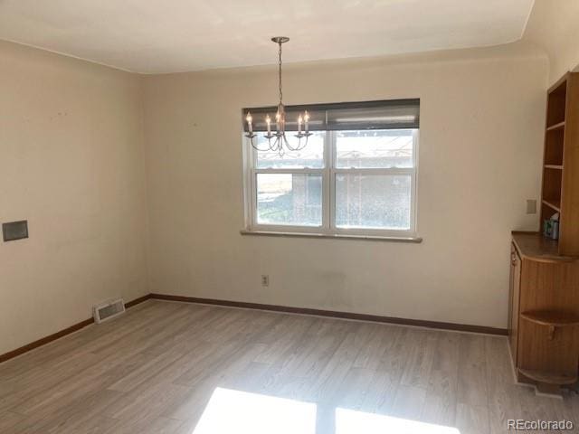 unfurnished dining area with an inviting chandelier and light hardwood / wood-style flooring