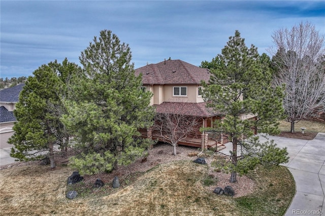 view of front of home featuring stucco siding, concrete driveway, and roof with shingles