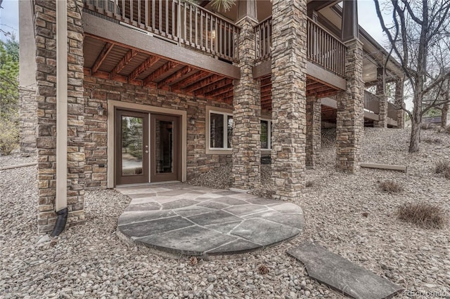 property entrance with stone siding, a patio, and a balcony
