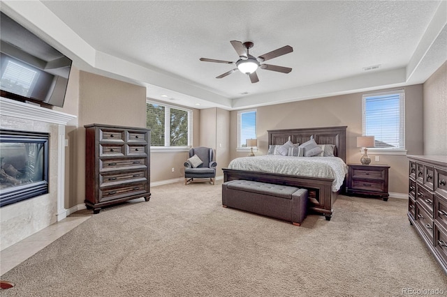 bedroom with light colored carpet, baseboards, a textured ceiling, visible vents, and a fireplace
