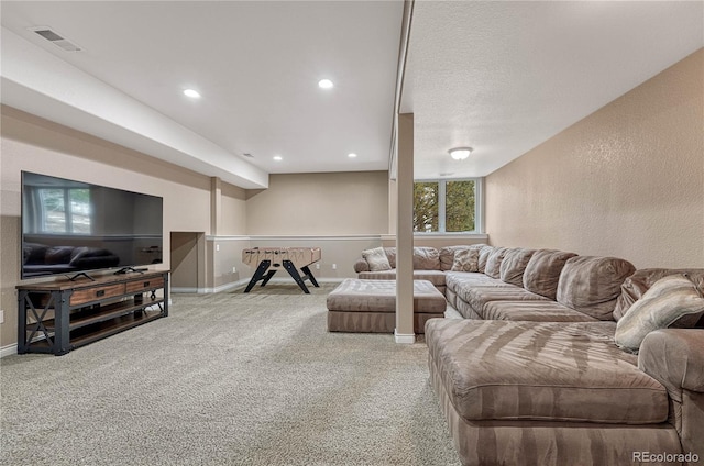 living room with a textured wall, carpet floors, visible vents, and baseboards
