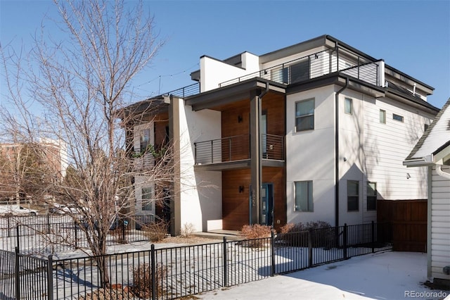 view of front of home with a fenced front yard, a balcony, and stucco siding