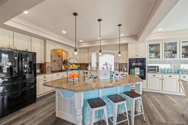 3871 Starry Night Loop, Castle Rock, CO 80109 - kitchen featuring black appliances, a tray ceiling, arched walkways, decorative backsplash, and a center island