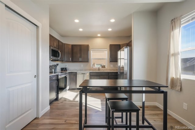 kitchen featuring dark brown cabinetry, sink, stainless steel appliances, and light wood-type flooring