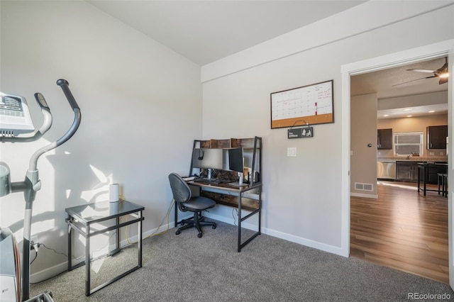 carpeted office space featuring ceiling fan