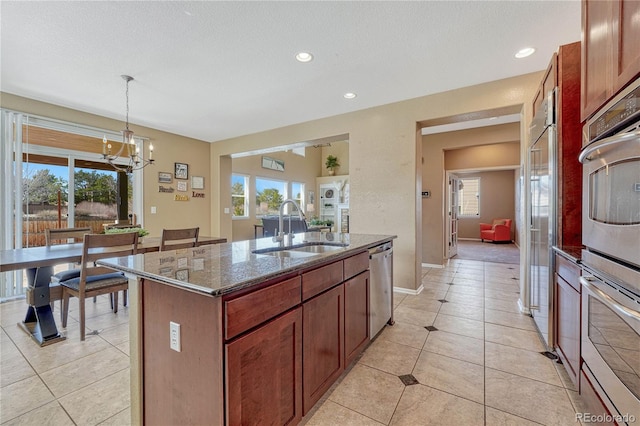 kitchen featuring dark stone counters, a healthy amount of sunlight, stainless steel appliances, and a sink