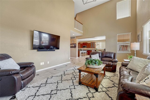 tiled living area with a high ceiling, baseboards, and visible vents