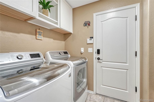 laundry room featuring a textured wall, cabinet space, and washer and clothes dryer