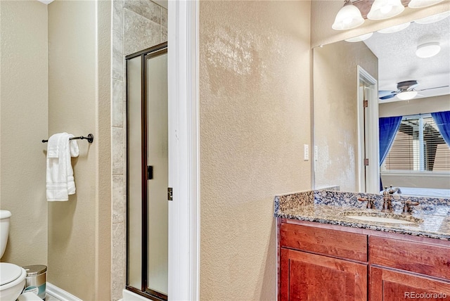 full bathroom featuring toilet, a stall shower, ceiling fan, vanity, and a textured wall