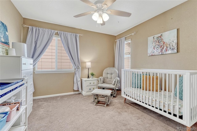 carpeted bedroom featuring baseboards, a nursery area, and ceiling fan