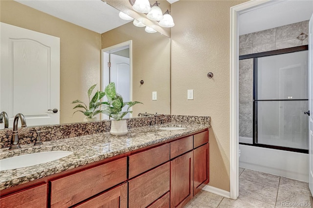 bathroom with double vanity, tile patterned floors, bath / shower combo with glass door, and a sink