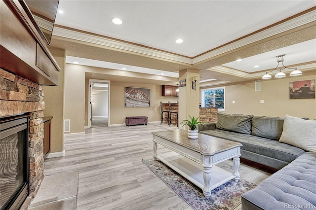 living room with baseboards, recessed lighting, a fireplace, ornamental molding, and light wood-type flooring