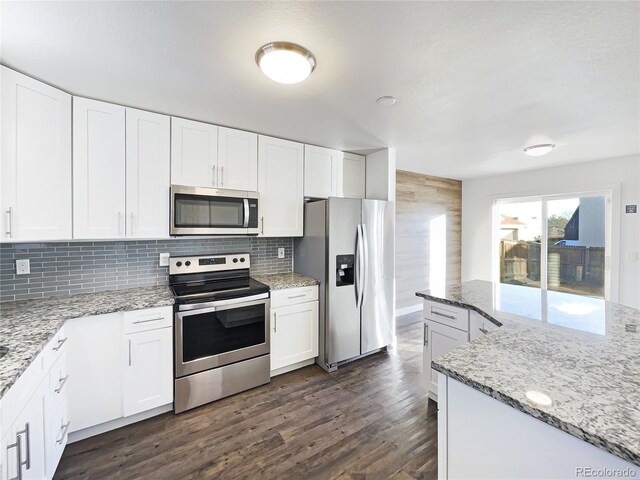 kitchen with appliances with stainless steel finishes, light stone counters, and white cabinets