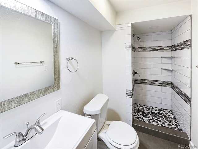 bathroom with toilet, vanity, and tiled shower