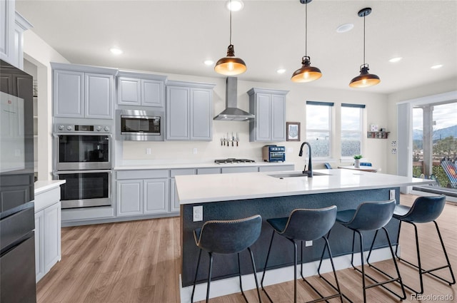 kitchen featuring sink, gray cabinets, stainless steel appliances, and wall chimney exhaust hood