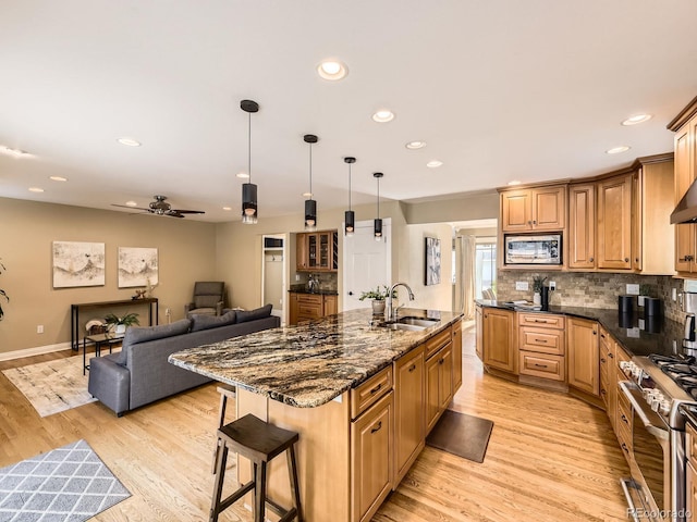 7826 S Niagara Way, Centennial, CO 80112 - kitchen featuring stainless steel appliances, light wood-type flooring, a breakfast bar area, an island with sink, and recessed lighting