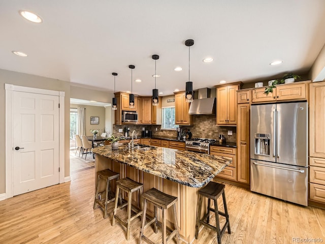 7826 S Niagara Way, Centennial, CO 80112 - kitchen with high end appliances, a breakfast bar area, light wood finished floors, wall chimney range hood, and recessed lighting