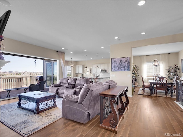 living area featuring wood-type flooring, a chandelier, plenty of natural light, recessed lighting, and baseboards
