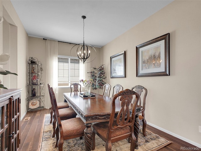 dining space featuring a chandelier, wood finished floors, and baseboards