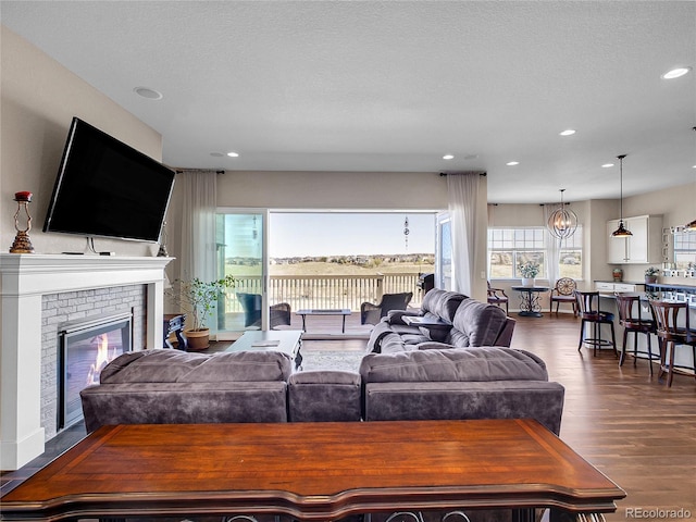 living area featuring dark wood-style flooring, recessed lighting, and a brick fireplace