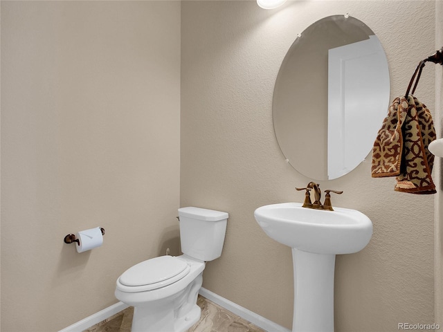 bathroom with toilet and baseboards