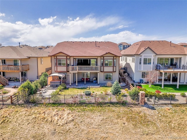 rear view of property with a hot tub, a fenced backyard, a balcony, a patio, and a residential view