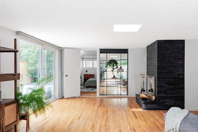 2525 S Meade St, Denver, CO 80219 - living room featuring plenty of natural light, light wood-type flooring, a skylight, a fireplace, and expansive windows