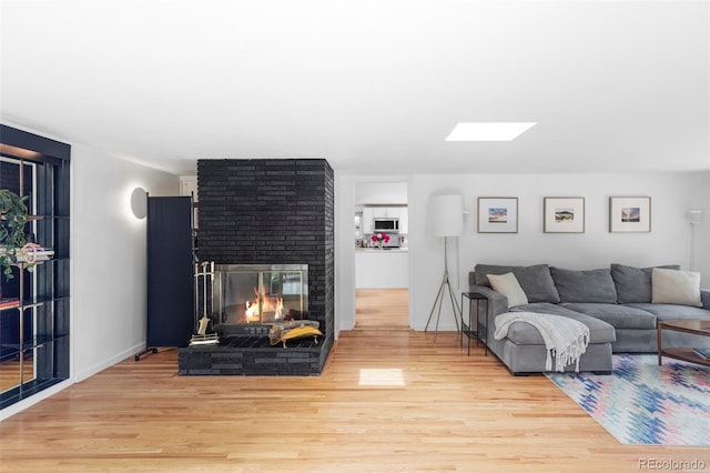 2525 S Meade St, Denver, CO 80219 - living area with wood finished floors, a brick fireplace, and a skylight
