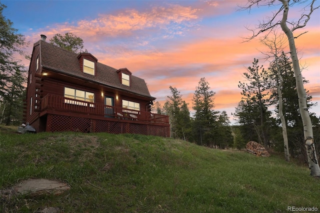143 Juniper Rd, Black Hawk, CO 80422 - back of property at dusk featuring a chimney, roof with shingles, a wooden deck, and log siding