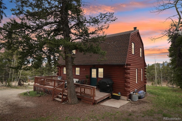 143 Juniper Rd, Black Hawk, CO 80422 - back of property at dusk with log siding, a shingled roof, a deck, and a gambrel roof