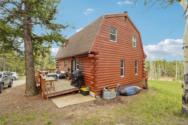 143 Juniper Rd, Black Hawk, CO 80422 - view of home's exterior featuring log exterior, roof with shingles, a deck, a gambrel roof, and a yard