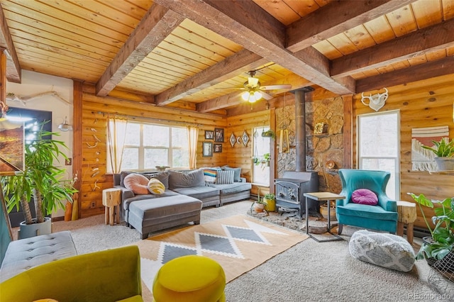 143 Juniper Rd, Black Hawk, CO 80422 - carpeted living room featuring a wood stove, wood ceiling with exposed beams, ceiling fan, and wood walls