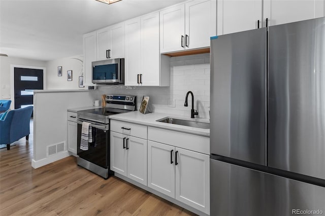 kitchen featuring white cabinetry, appliances with stainless steel finishes, sink, and light hardwood / wood-style flooring