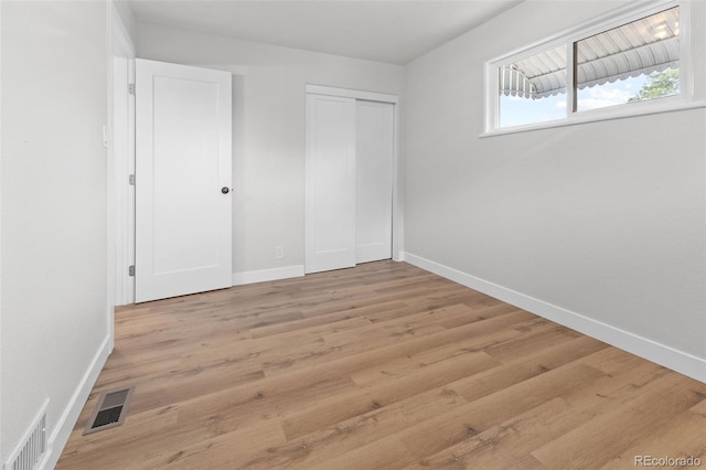 unfurnished bedroom with light hardwood / wood-style floors and a closet