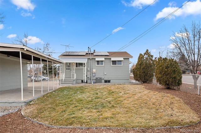 rear view of house featuring a patio, a yard, central AC, and solar panels