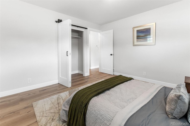 bedroom featuring a closet, a barn door, and light wood-type flooring