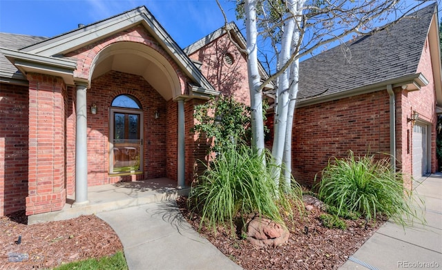 2425 Waneka Lake Trl, Lafayette, CO 80026 - doorway to property featuring brick siding, a shingled roof, driveway, and a garage