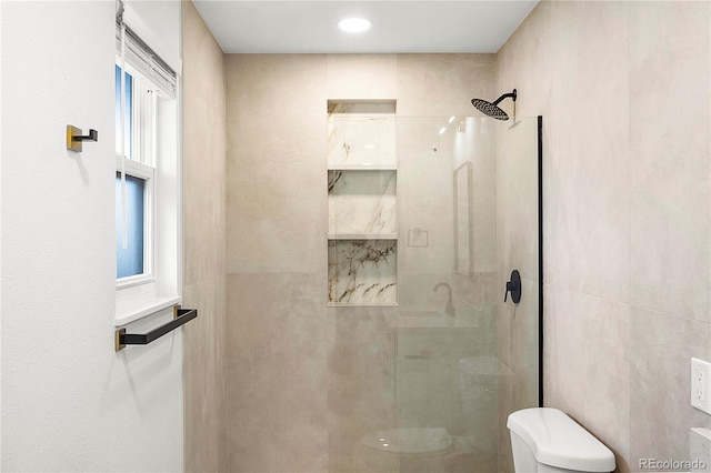 bathroom featuring tiled shower and toilet