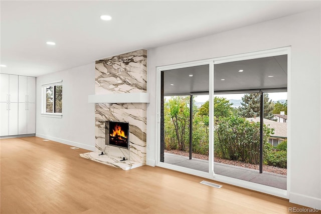 unfurnished living room with wood-type flooring and a high end fireplace