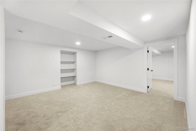 basement with built in shelves and light colored carpet