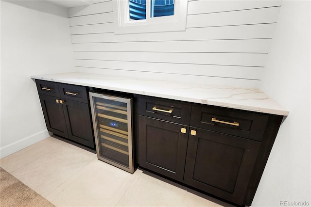 bar featuring light tile patterned floors, wine cooler, and light stone countertops