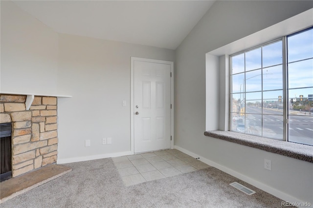 carpeted foyer featuring vaulted ceiling and a fireplace