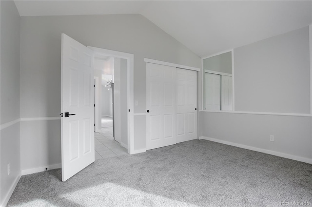 unfurnished bedroom with vaulted ceiling, light carpet, and a closet